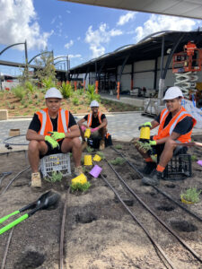 (L-R): Wildflower crew members Malakai, Trangi, and Chaise during the Sydney Airport installation