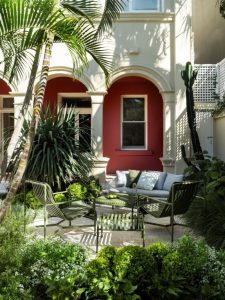 A rich backdrop accentuates the elegant curves of the architecture, while lush textural plantings soften the heavy columns and encourage a sense of discovery